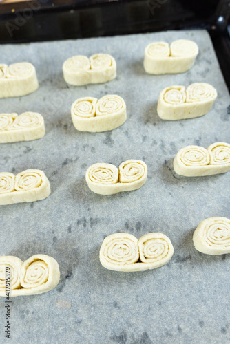 homemade cakes on a baking sheet, raw puff pastry in the form of cookies, cookies ears
