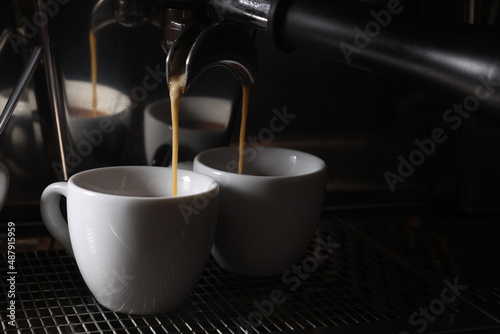 Making fresh aromatic espressos using professional coffee machine in cafe, closeup. Space for text