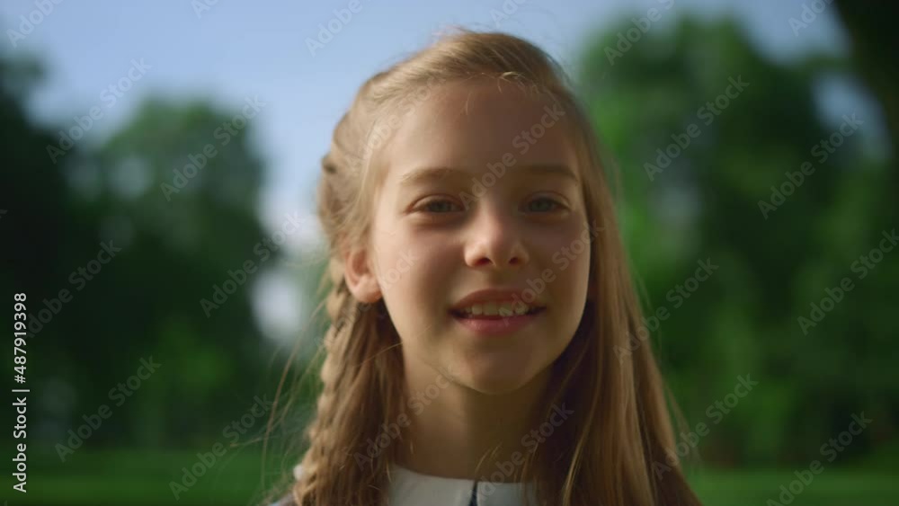 Smiling blonde little girl posing alone in park closeup. Romantic dreamy child Smiling blonde little girl posing alone in park closeup. Romantic dreamy child