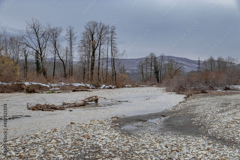 Landscape on a cloudy day with a fast - flowing mountain river . A cloudy day in the foothills of the Caucasus. The flood of the river during the melting of snow. Landscape on a cloudy day with a fast - flowing mountain river . A cloudy day in the foothills of the Caucasus. The flood of the river during the melting of snow.