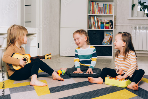 Smiling children playing musical instruments at home. Brother and sisters have fun in the room