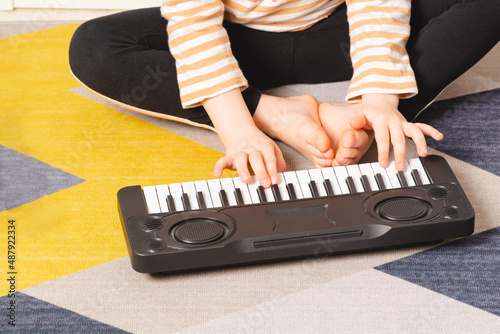 Close-up of a child's hands playing the small piano. Leisure and education at home