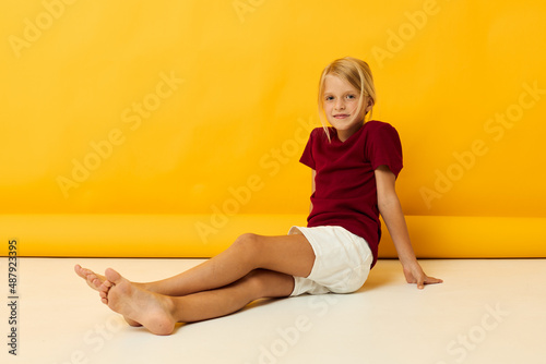 Girl sitting on the floor posing yellow background