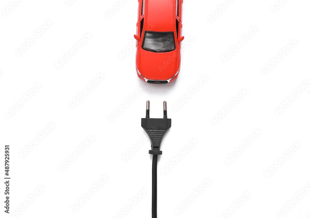 Toy car model with an electric plug on a white background. Electric car Toy car model with an electric plug on a white background. Electric car