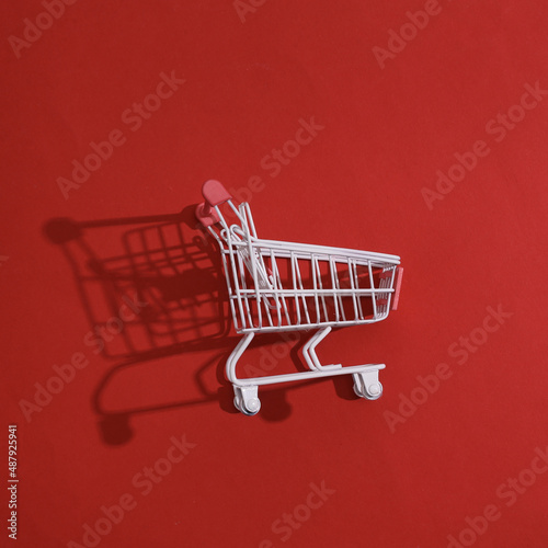 White supermarket trolley with shadow on red background