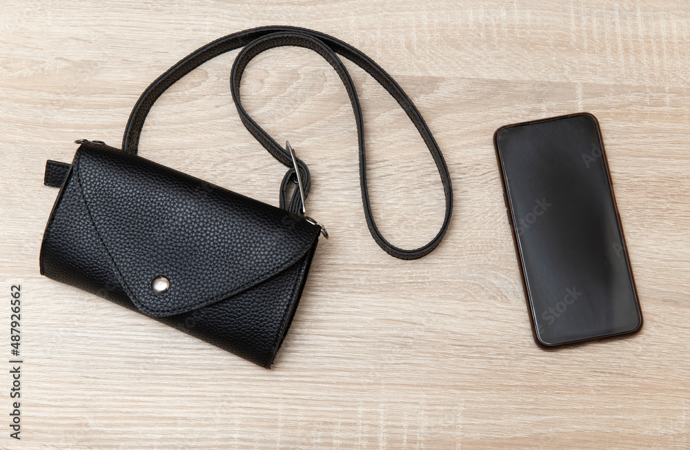 Leather handbag with smartphone on a wooden table. Top view Leather handbag with smartphone on a wooden table. Top view