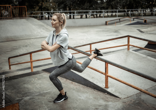 Attractive slim woman practicing lunge on skate ground. Outdoor sports