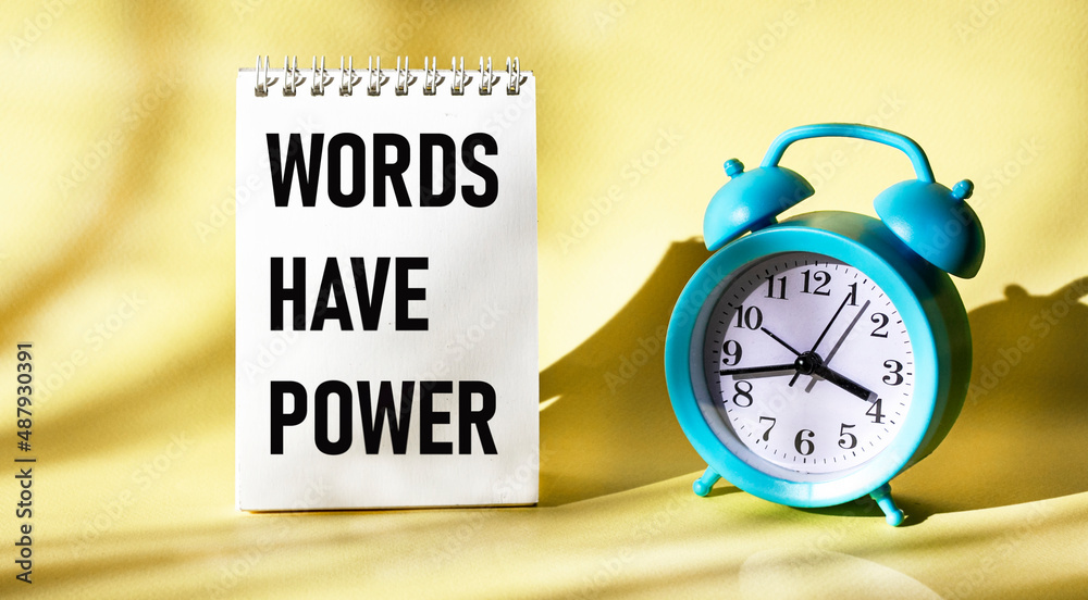 Words have power, text in a notepad on a yellow background with a clock Words have power, text in a notepad on a yellow background with a clock