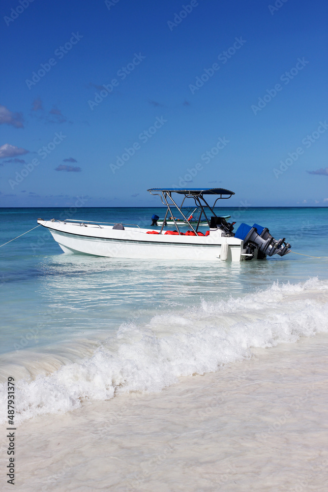 Fototapeta premium White boat in the open sea against a blue sky with white clouds on the horizon