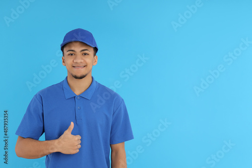 Young delivery man in cap on blue background