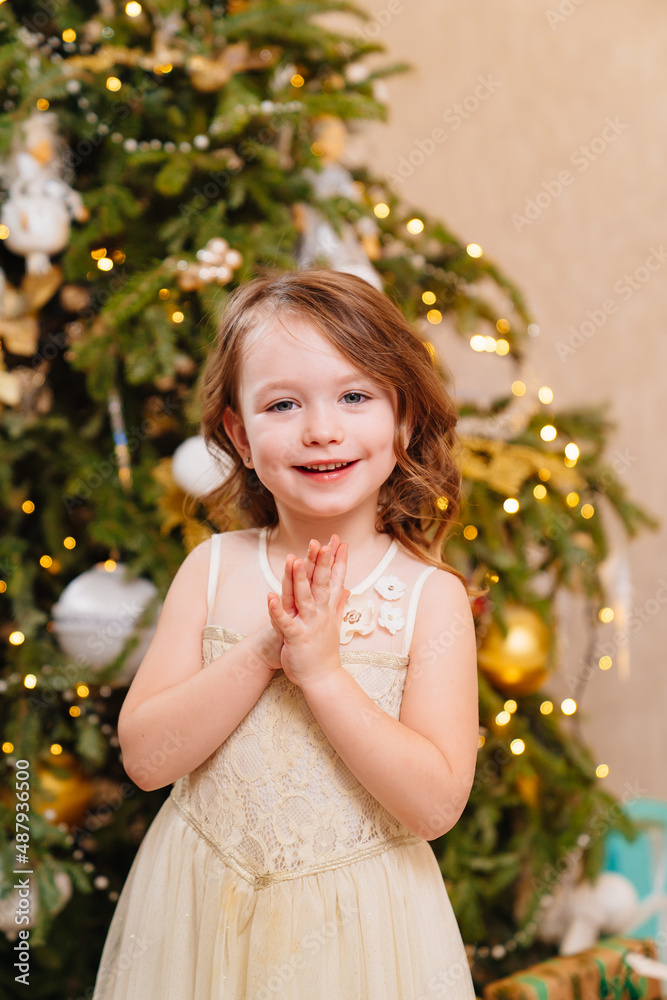 a cute little girl makes a wish and waits for Santa Claus at the Christmas tree.