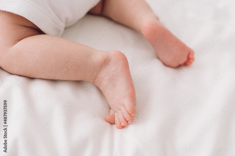 legs of newborn baby on white sheet close-up, baby learns to crawl legs of newborn baby on white sheet close-up, baby learns to crawl