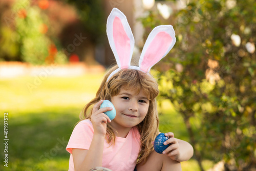 Child boy hunting easter eggs. Kid with easter eggs and bunny ears outdoor. Spring holidays.