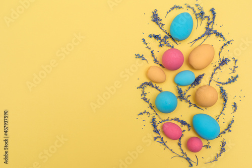 Flat lay Easter pastel colored eggs on yellow background