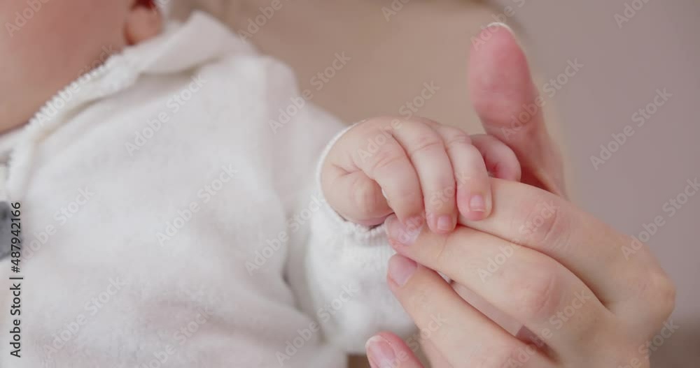 A newborn baby holds a mother's finger with her little pen. Mom gently strokes the baby's little pen A newborn baby holds a mother's finger with her little pen. Mom gently strokes the baby's little pen