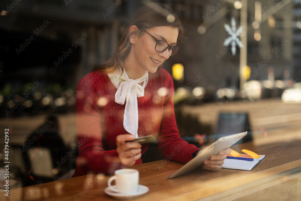 Happy woman using credit card to shopping online with tablet. Beautiful young woman drinking coffee in cafe.. Happy woman using credit card to shopping online with tablet. Beautiful young woman drinking coffee in cafe..