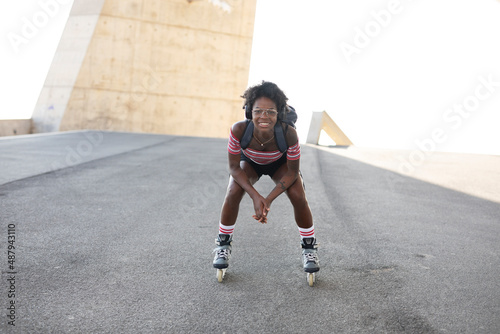 Beautiful woman with roller skates. Urban happy girl with curly hair enjoy in sunny day