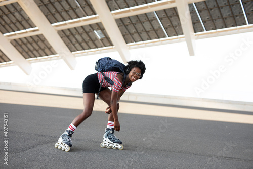 Beautiful woman with roller skates. Urban happy girl with curly hair enjoy in sunny day