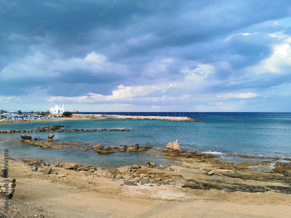 Rocky shore with sand, sandy beach, the temple of St. Nicholas the Wonderworker against the backdrop of a dramatic sky. Rocky shore with sand, sandy beach, the temple of St. Nicholas the Wonderworker against the backdrop of a dramatic sky.
