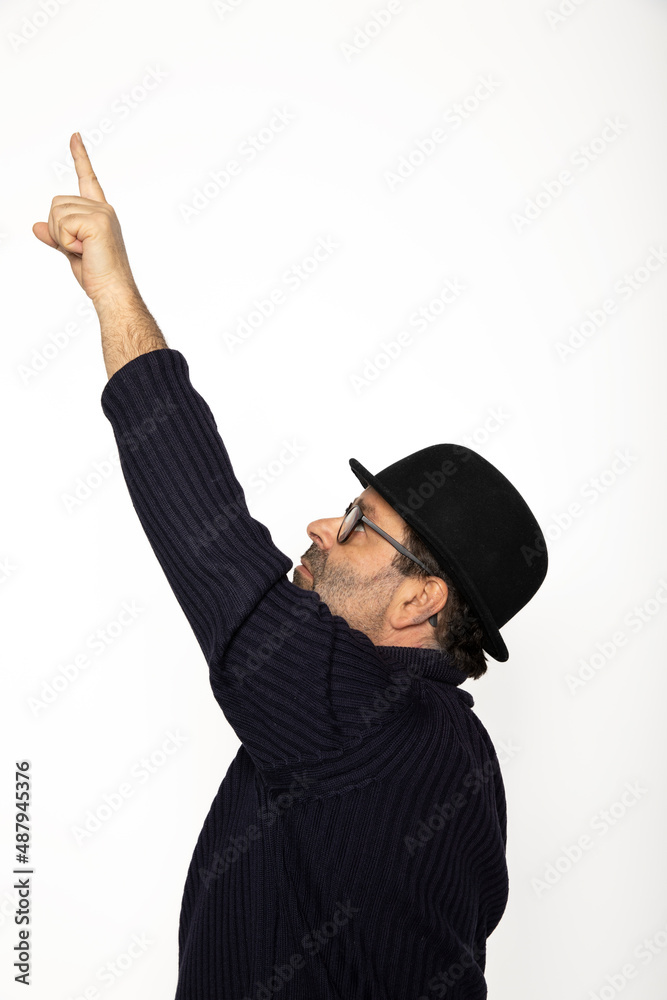 Man in profile points upward with his finger. He is wearing a blue sweater, jeans and a bowler hat Man in profile points upward with his finger. He is wearing a blue sweater, jeans and a bowler hat