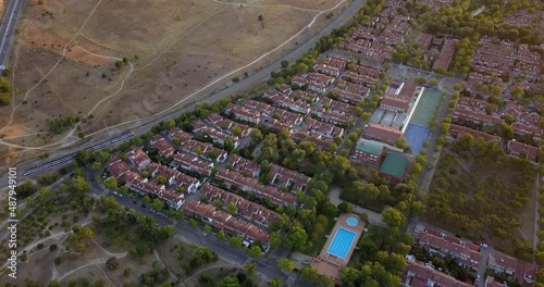 Aerial drone view of set of townhouses with a train passing next to them in Aravaca, Madrid photo