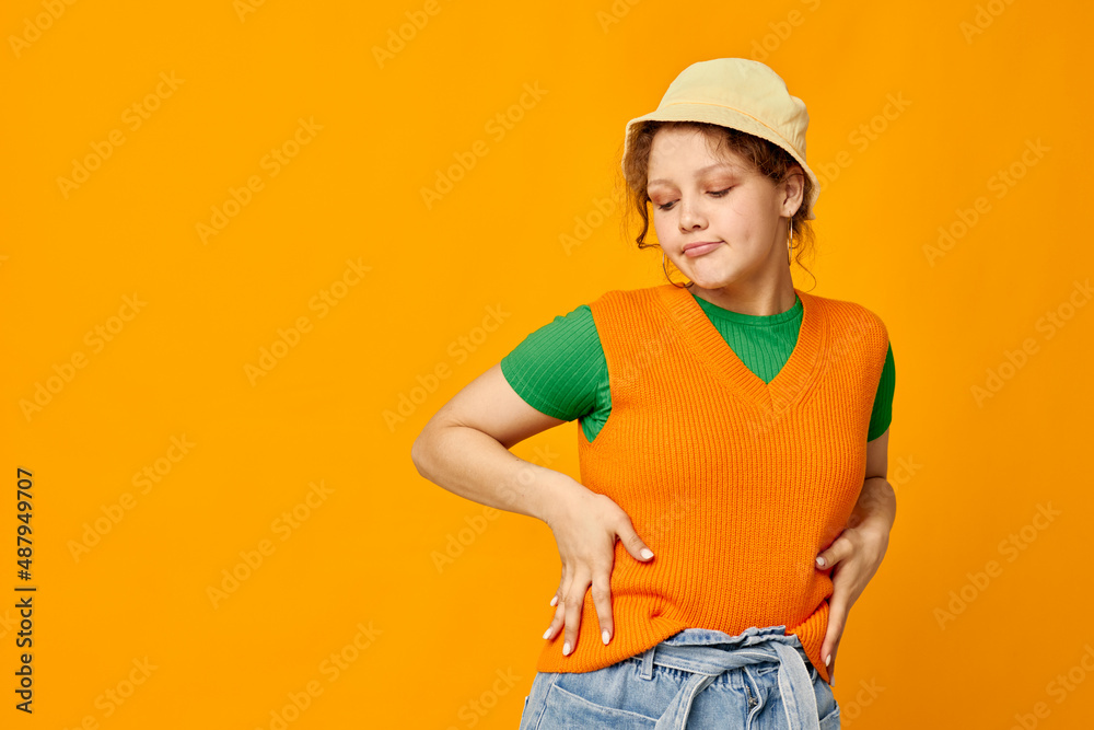 cute girl wearing hat posing orange sweater isolated background
