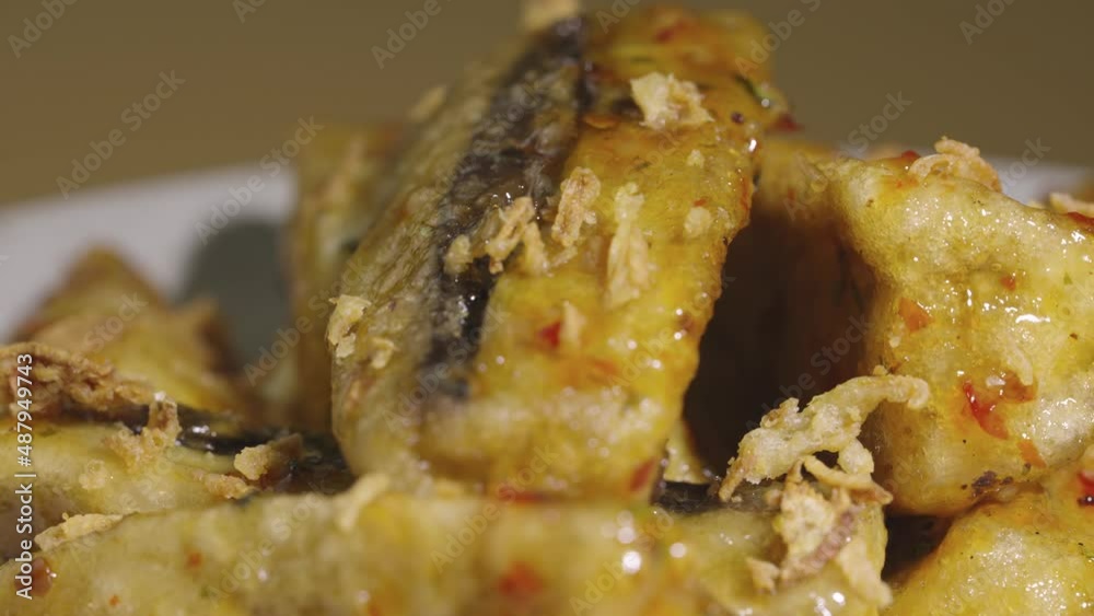 Tempura aubergine slices with spicy spices and cane sugar syrup on grey