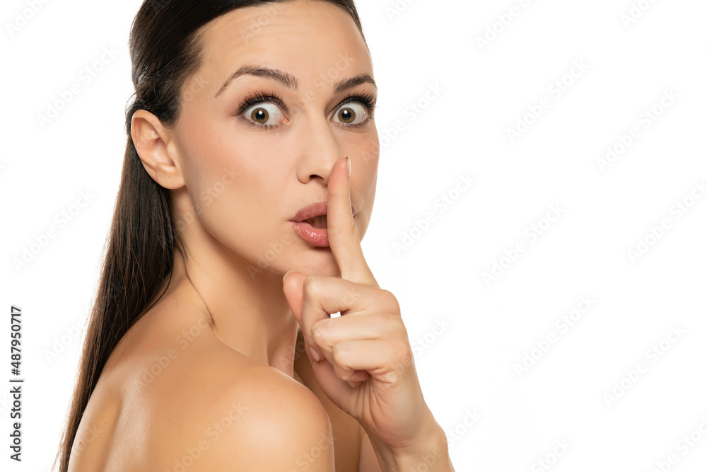 Excited young woman with a finger on her lips Excited young woman with a finger on her lips