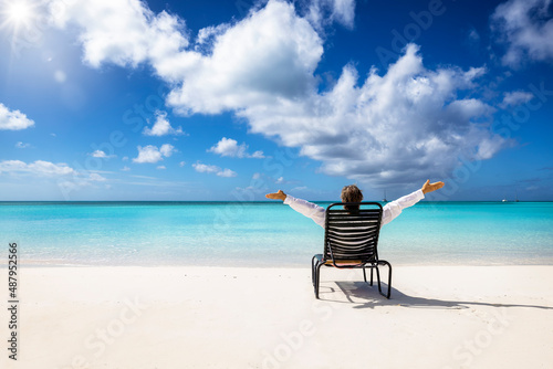 Slika na platnu A happy man relaxes in a chair on a tropical paradise beach in the Caribbean wit