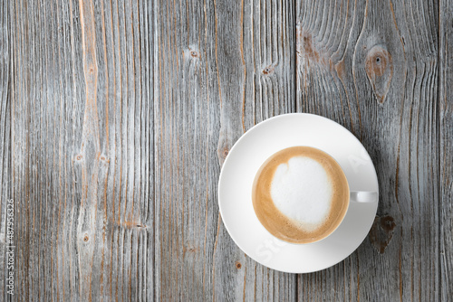 Fragrant cappuccino in white cup flat lay gray wood background. Cappuccino on wooden background flat lay.