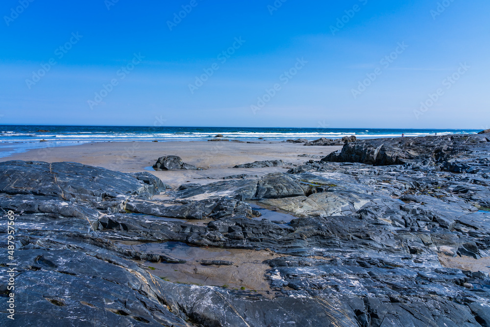 Smooth stone slabs among clean sand at low tide against the backdrop of the Atlantic Ocean on Hampton Beach