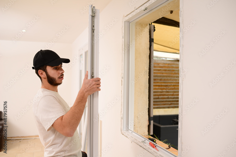 handsome young professional man installing and replacing a new home windows in client house for improvement energy saving efficiency isolation handsome young professional man installing and replacing a new home windows in client house for improvement energy saving efficiency isolation