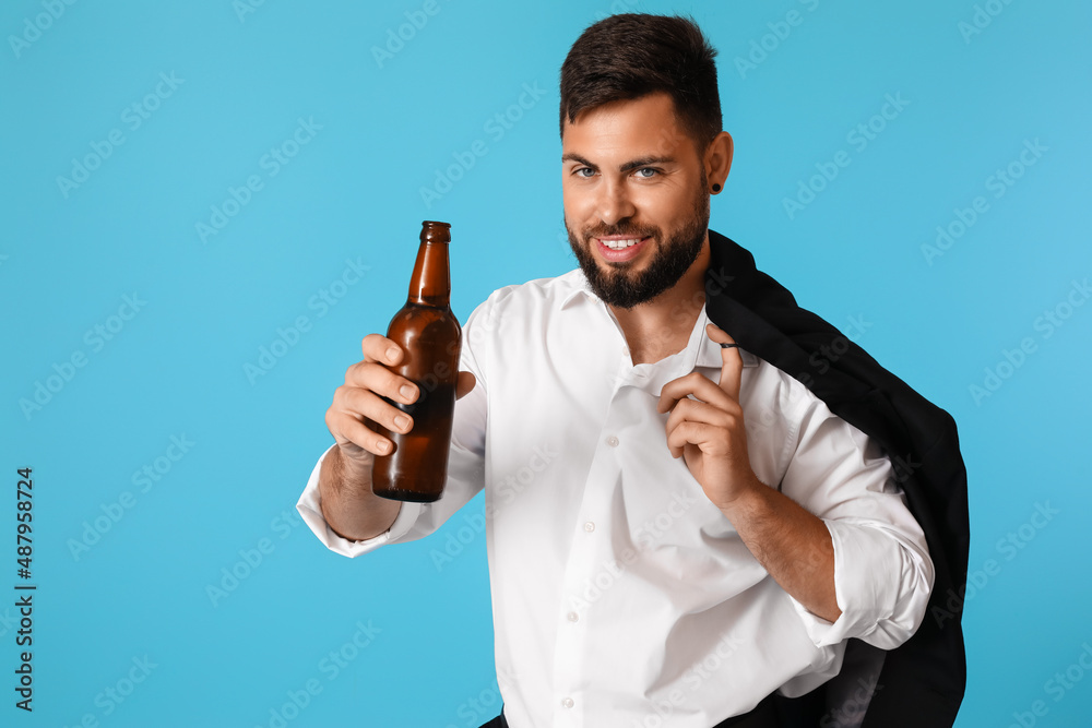 Young businessman with bottle of beer on blue background Young businessman with bottle of beer on blue background