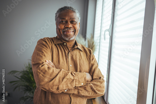 African American Senior Man at home Portrait. Smiling senior man looking at camera. Portrait of black confident man at home. Portrait of a senior man standing against a grey background