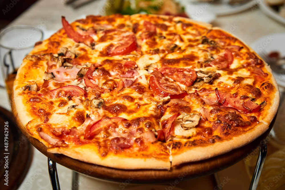Pizza with salami, bell pepper, tomatoes and cheese, pickles, bacon and sausages on a light background. Close-up, selective focus