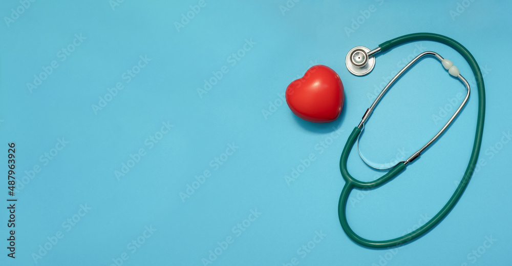 Stethoscope with red heart on blue background. Heart diseases. Doctors Day, Healthcare and Medicine concept Stethoscope with red heart on blue background. Heart diseases. Doctors Day, Healthcare and Medicine concept