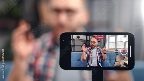 Friendly male blogger recording video use smartphone screen communicating to audience gesticulating photo