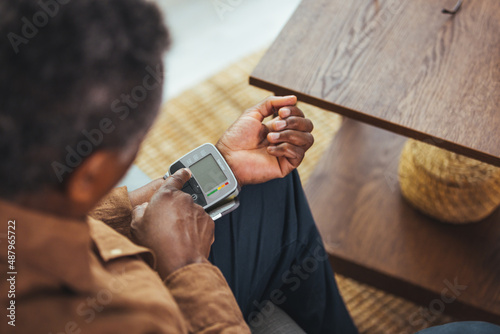 Hypertension In Older Age. Senior Black Man Measuring Arterial Blood Pressure Having Problems With Tension, Using Blood-Pressure Cuff Sitting On Sofa At Home. Healthcare And Medicine Concept photo