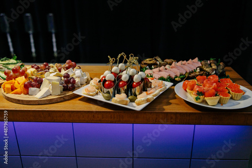 Meal. Festive buffet table for guests. Assortment of cold cuts,canapes on wooden skewers, festive snacks with fruits and salads. Reception at the party.