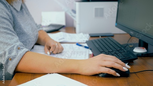 Woman working on computer in office. Scrolling through a spreadsheets