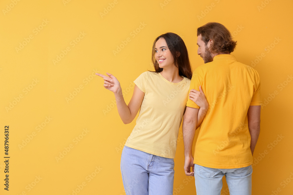 Young couple in stylish t-shirts on yellow background Young couple in stylish t-shirts on yellow background