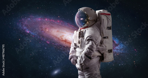 Astronaut in bright space with galaxy Andromeda. Spaceman with starry and galactic background. Sci-fi wallpaper. Elements of this image furnished by NASA