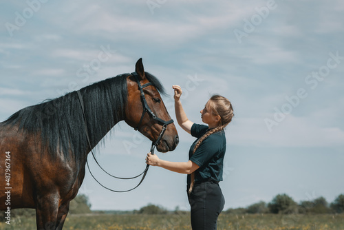 Caucasian woman holding reins of horse with hand in outdoors.