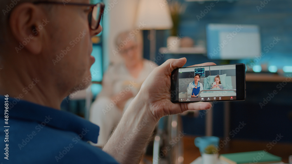 Elderly adult using video call to talk to doctor about health of little girl. Worried grandfather starting remote discussion with medic and niece on online teleconference call for telemedicine.