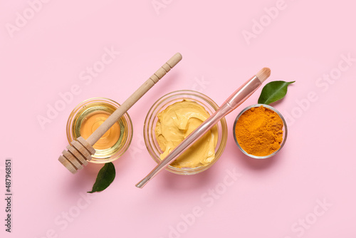 Bowls with turmeric mask, powder and honey on pink background