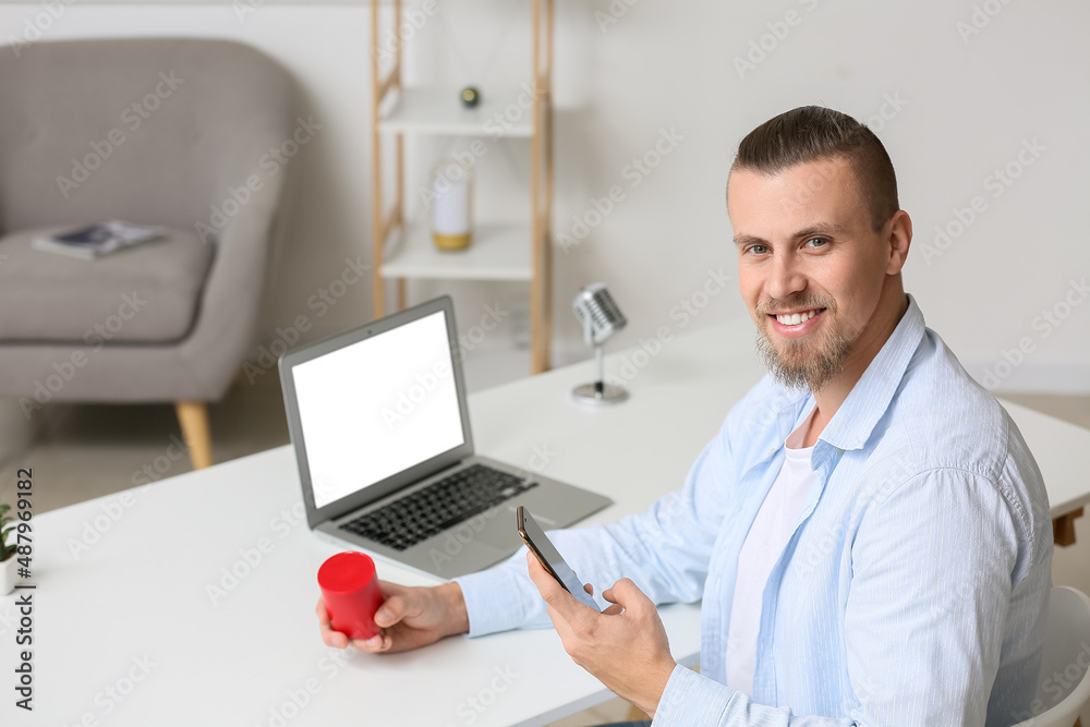 Man connecting mobile phone to wireless portable speaker on table Man connecting mobile phone to wireless portable speaker on table