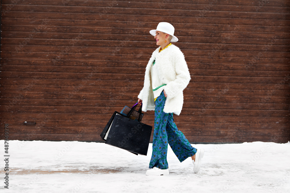 Mature fashionable woman walk at winter street with shopping bags Mature fashionable woman walk at winter street with shopping bags