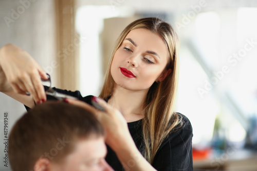 A beautiful woman cuts a man's hair with scissors, close-up