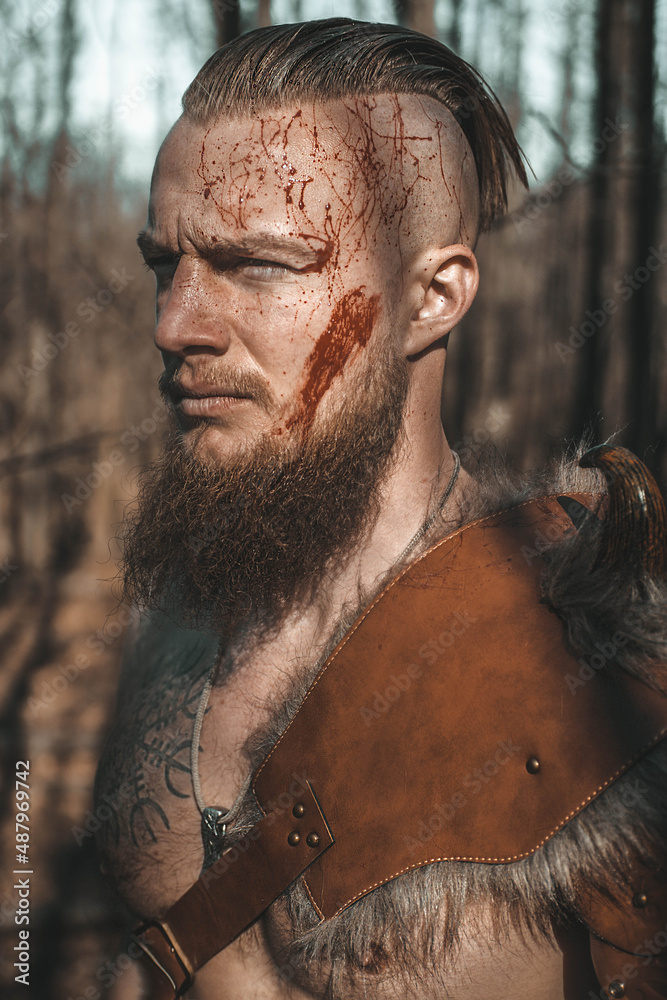 A medieval warrior Viking with a beard and a muscular physique poses