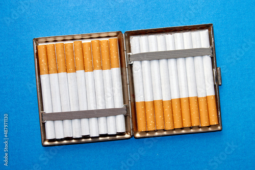 top view of tobacco filter cigarettes in a cigarette case, on blue background photo